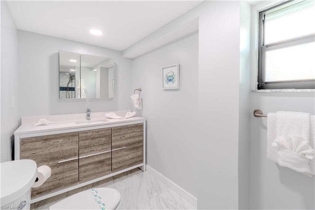 Bathroom featuring vanity and light marble tile finish floors - Virtually Edited Image