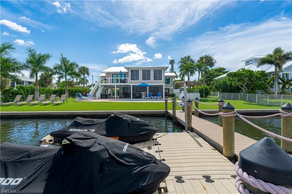 Dock featuring stairs, a water view, a patio area, and a balcony - Virtually Edited Image