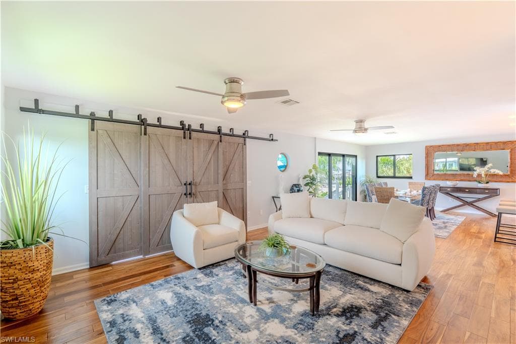Living room with ceiling fan, wood finished floors, and a barn door - Virtually Edited Image