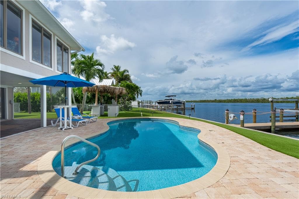 pool with a water view, a patio, a dock, and boat lift - Virtually Edited Image