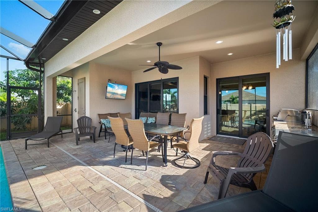 View of patio with outdoor dining area, a sunroom, glass enclosure, and ceiling fan