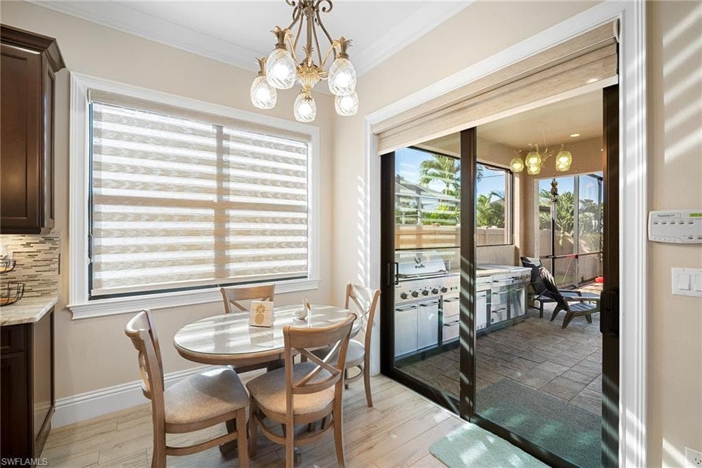 Dining area featuring a chandelier, light wood-style floors, and crown molding