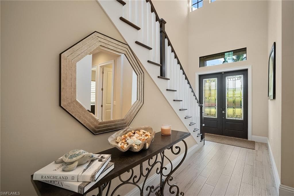Entrance foyer featuring wood finished floors, french doors, stairs, and a high ceiling