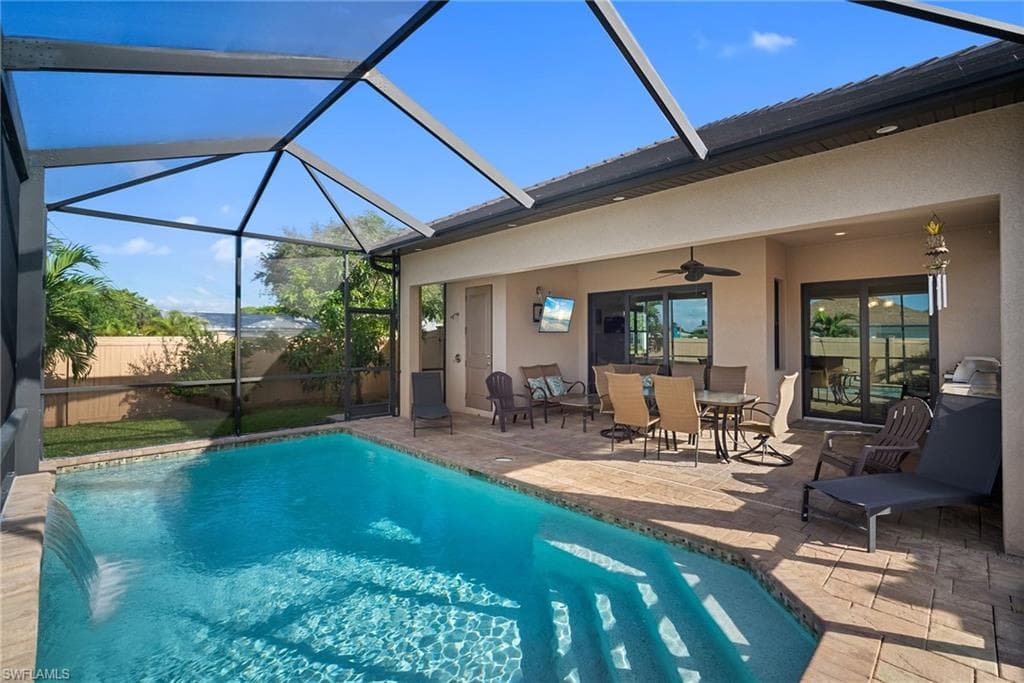 View of swimming pool with a sunroom, outdoor dining area, a lanai, ceiling fan, and a patio area