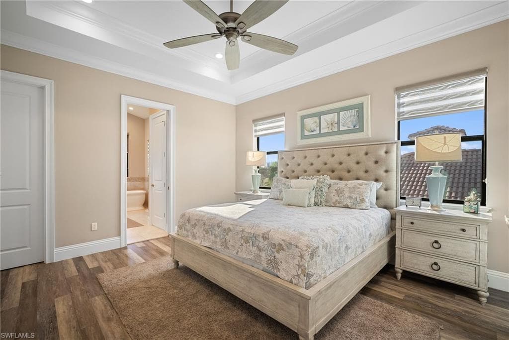 Bedroom with a raised ceiling, dark wood-style flooring, crown molding, recessed lighting, and a ceiling fan