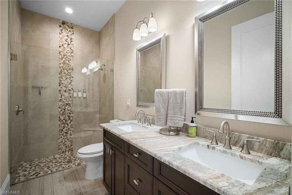 Bathroom featuring double vanity, a stall shower, and light wood-style floors