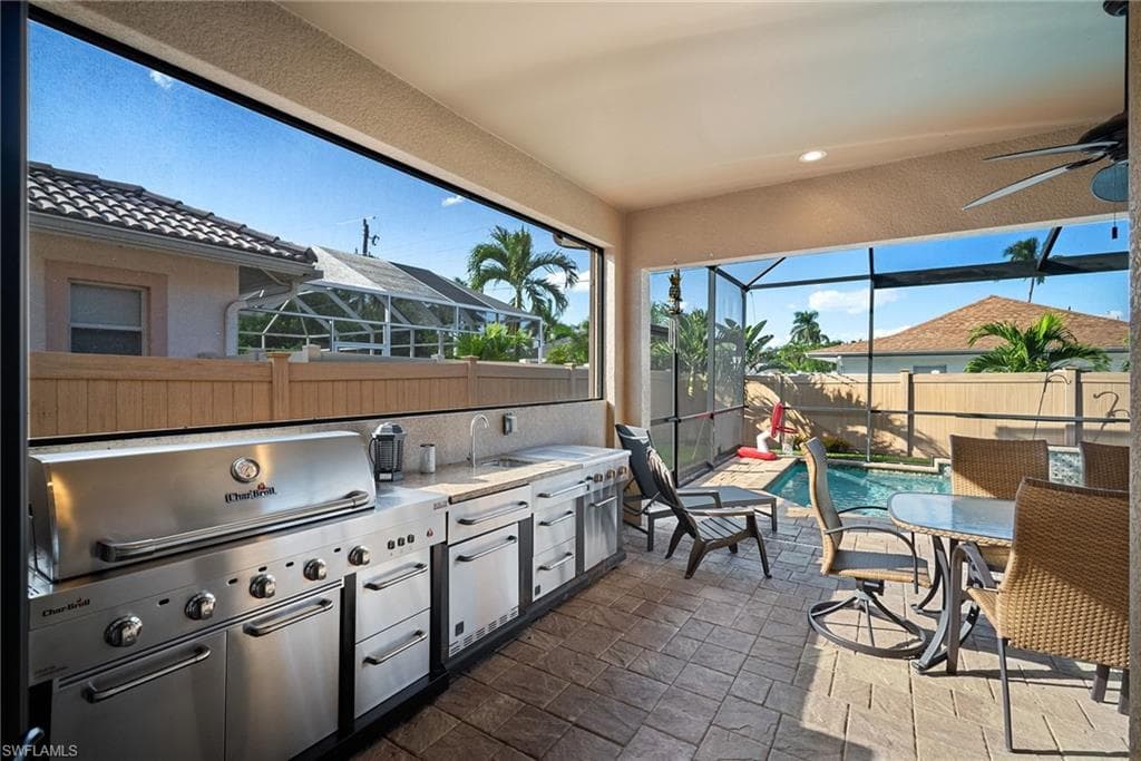 Fenced backyard with exterior kitchen, a patio area, a lanai, a sunroom, and outdoor dining space