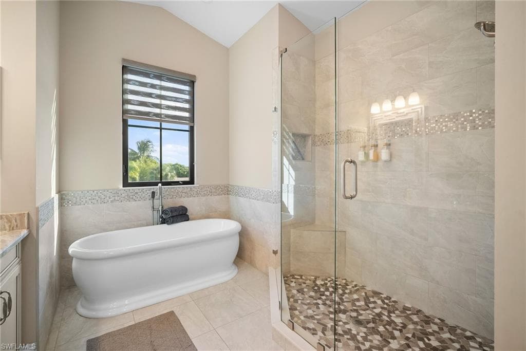 Bathroom featuring vanity, tile walls, a freestanding tub, a wainscoted wall, and a stall shower