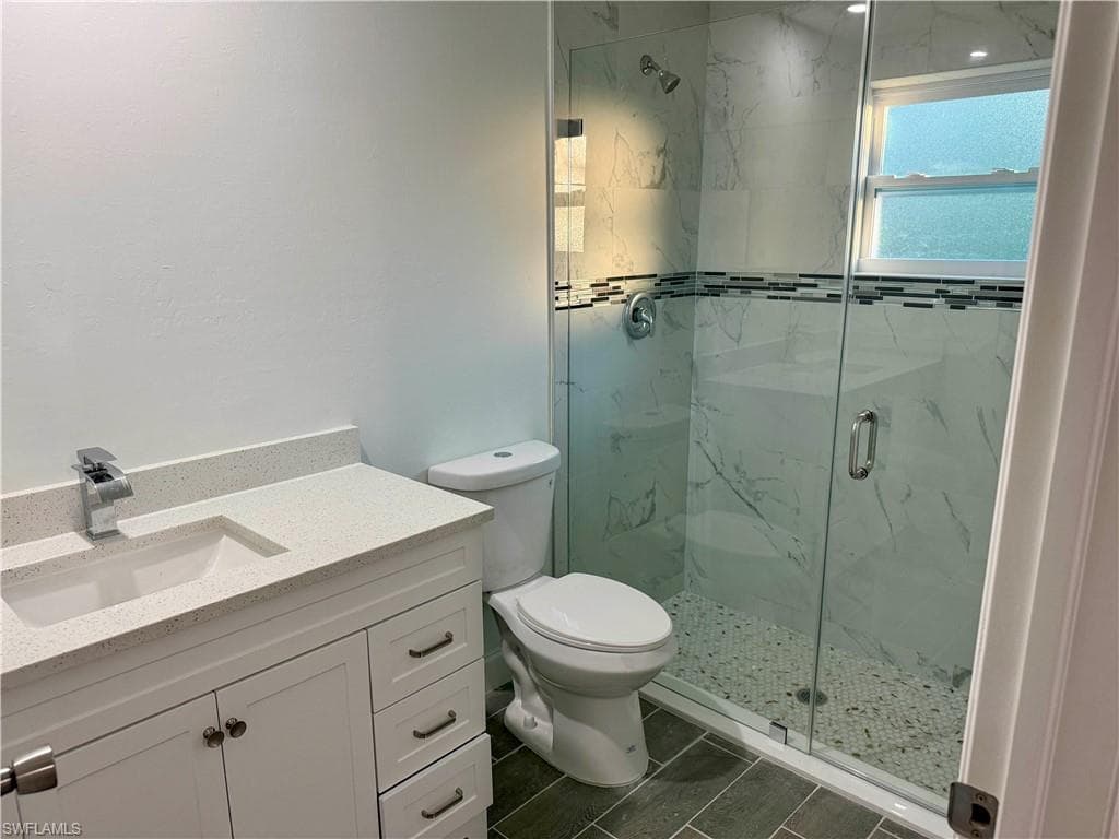 Full bath featuring vanity and a marble finish shower
