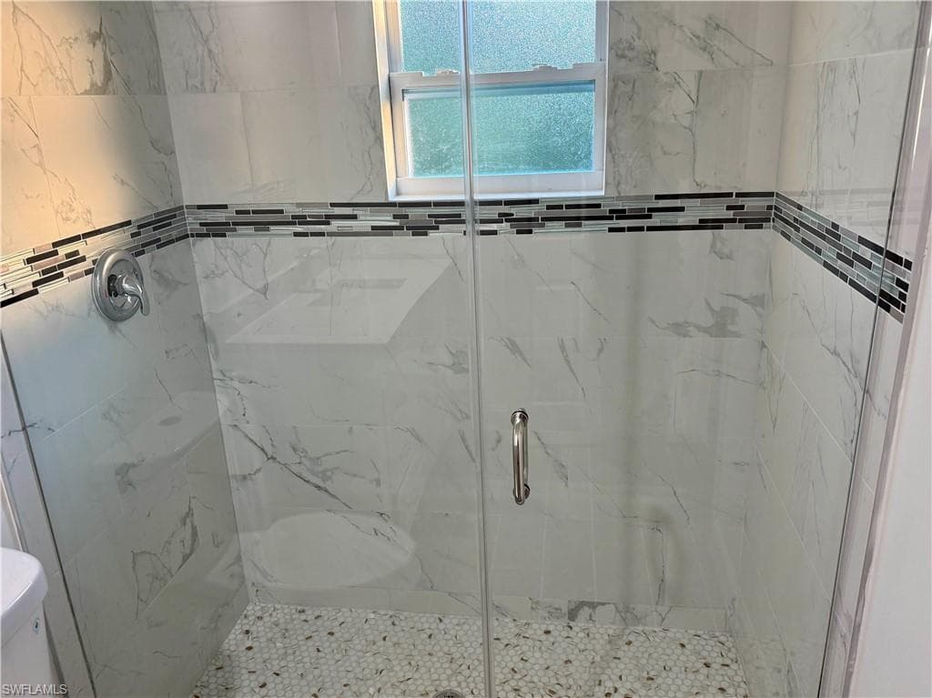 Bathroom with a marble finish shower and toilet