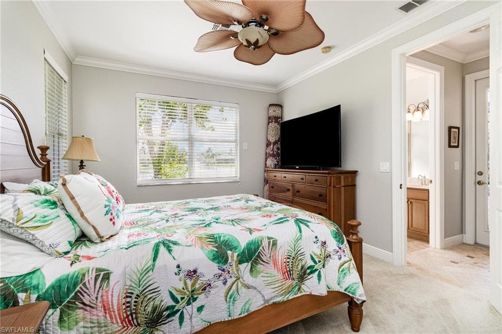 Bedroom featuring ornamental molding, light colored carpet, ceiling fan, and ensuite bath