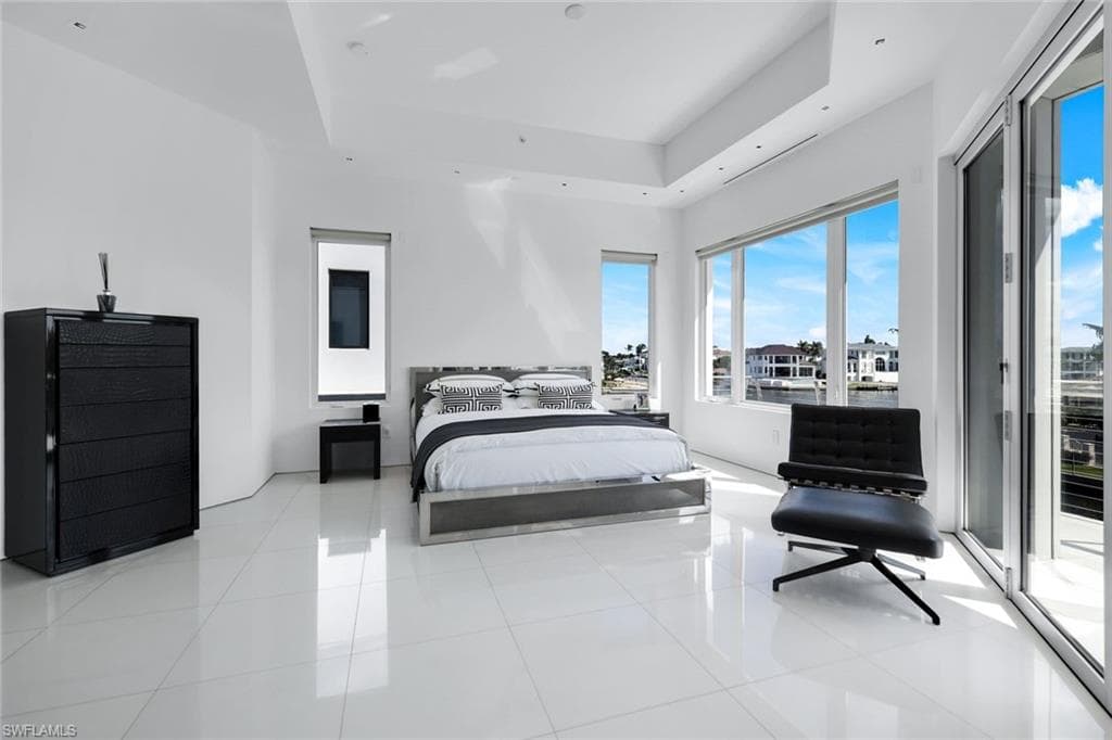 Bedroom with access to exterior, a raised ceiling, and light tile patterned floors
