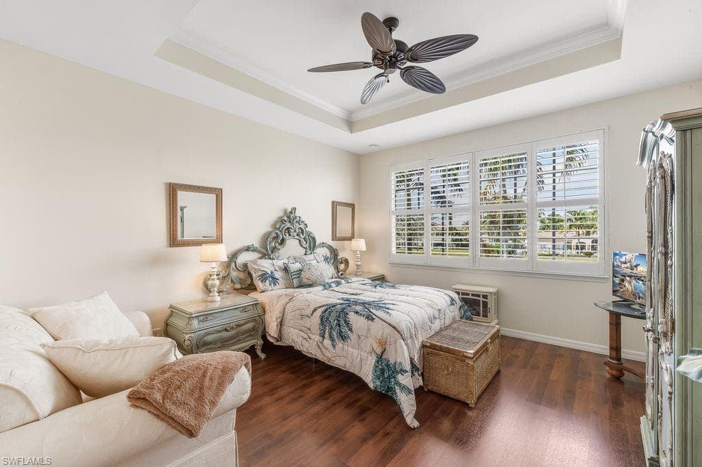 Master Bedroom with a tray ceiling, ornamental molding, LVT flooring, a ceiling fan, and plantation shutters