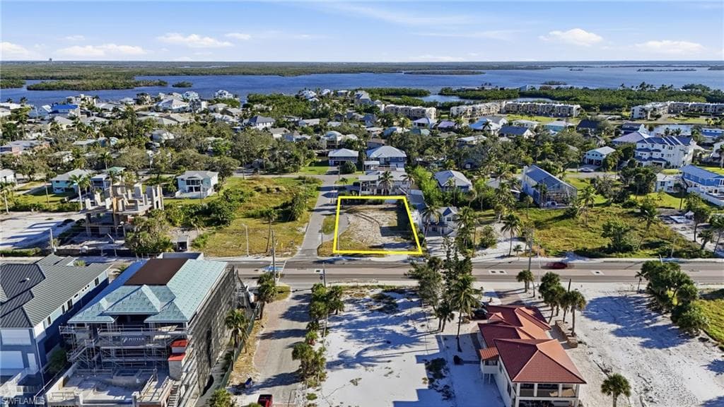 Aerial view of residential area with property parcel outlined and a large body of water - Virtually Edited Image