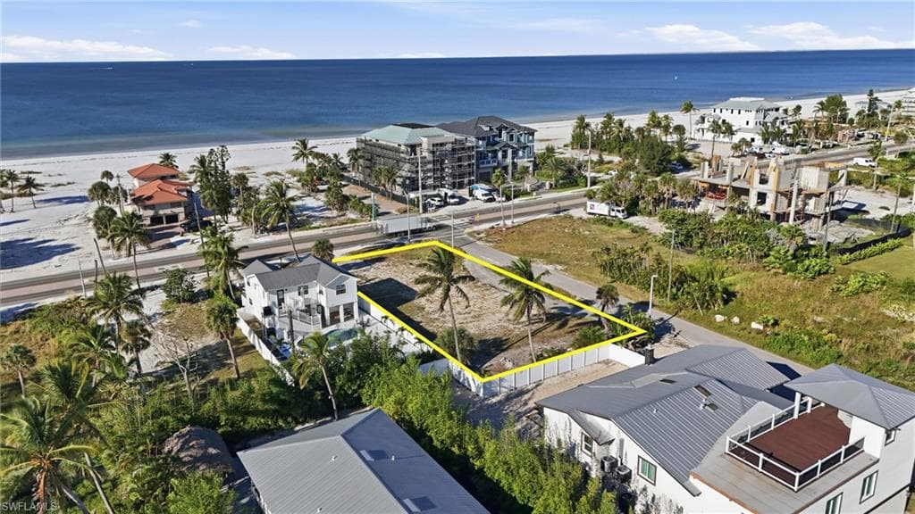 Aerial view of property and surrounding area with property parcel outlined and waterfront with a beach - Virtually Edited Image