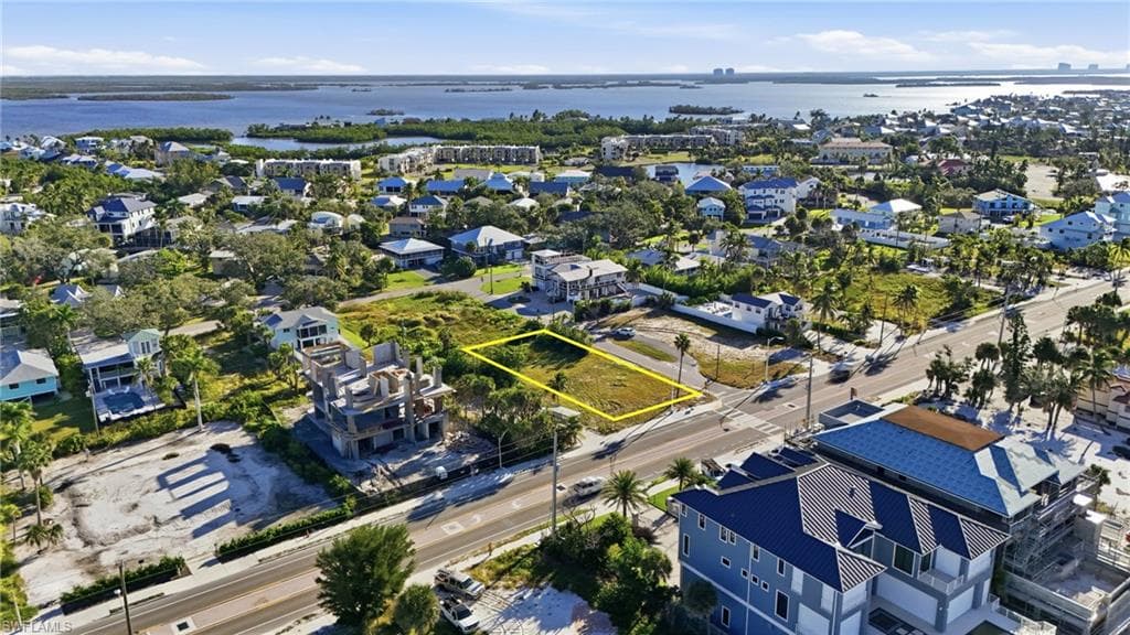 Aerial view of residential area with property boundaries highlighted and a nearby body of water - Virtually Edited Image
