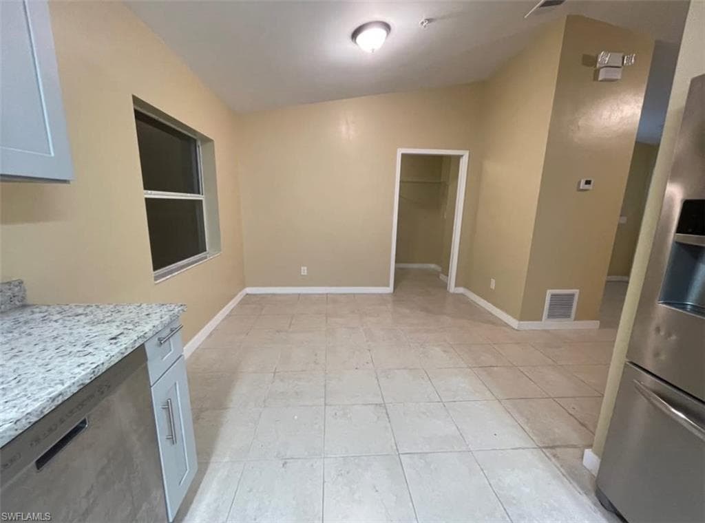 Unfurnished dining area featuring vaulted ceiling and light tile patterned floors