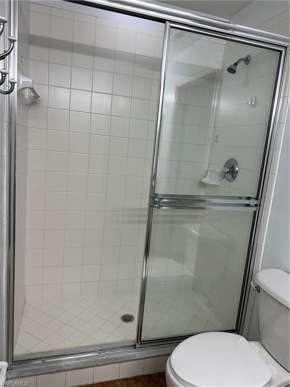 Bathroom featuring a shower with shower door and toilet