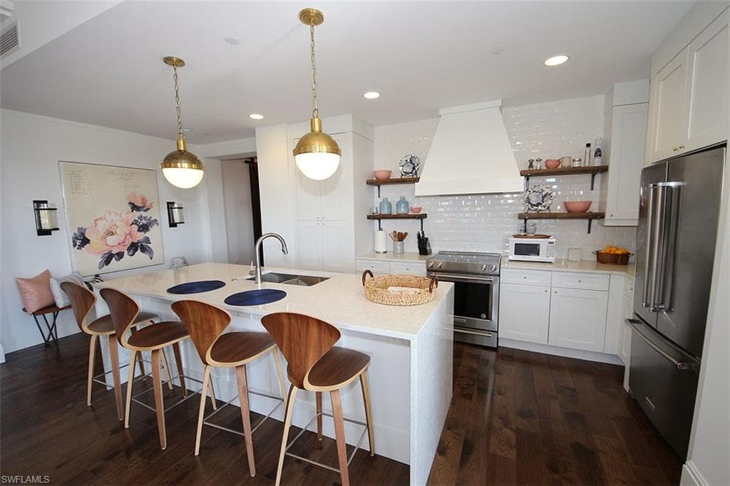 Kitchen with open shelves, white cabinets, high quality appliances, premium range hood, and recessed lighting
