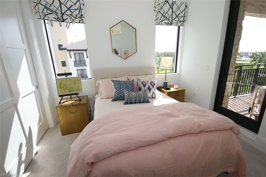 Bedroom featuring carpet, multiple windows, and access to exterior
