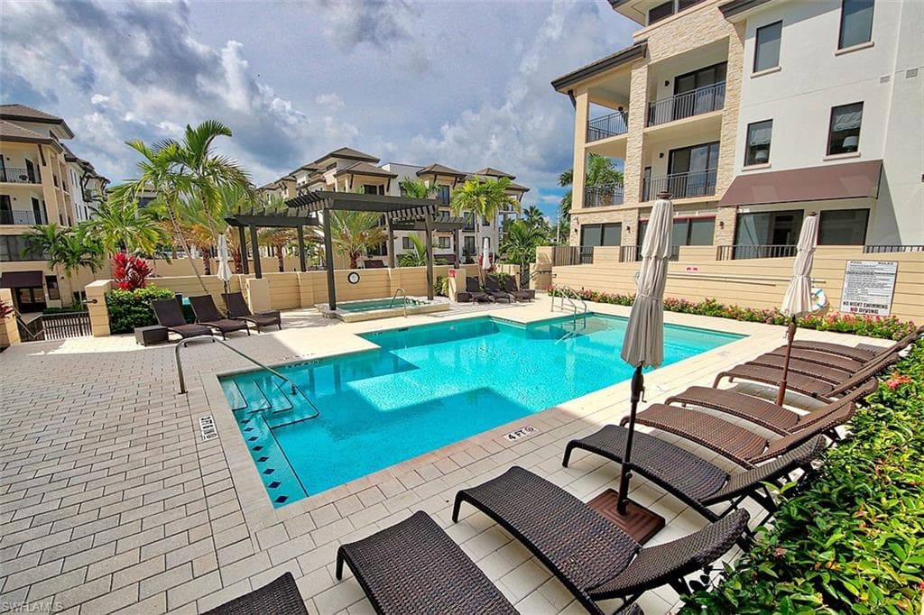 Community pool with a pergola, a hot tub, and a patio area