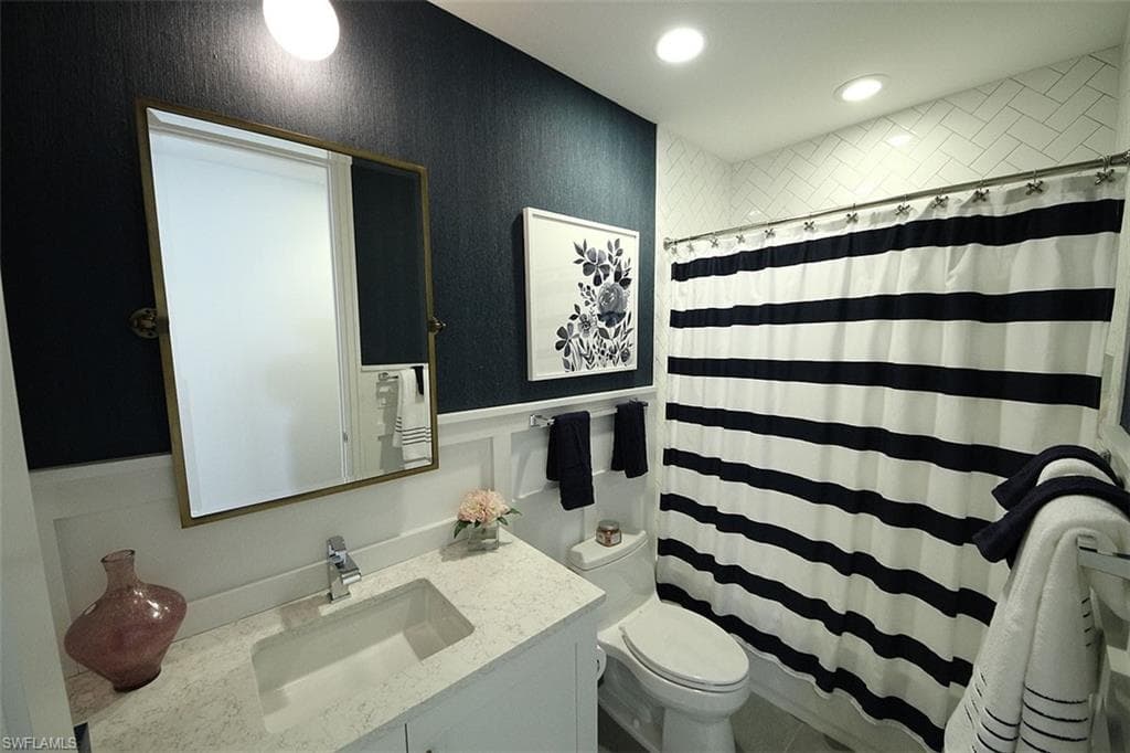Bathroom with a shower with shower curtain, vanity, and recessed lighting