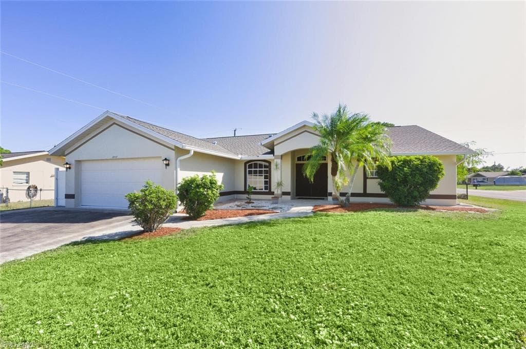 Ranch-style home featuring stucco siding, driveway, a front yard, and a shingled roof