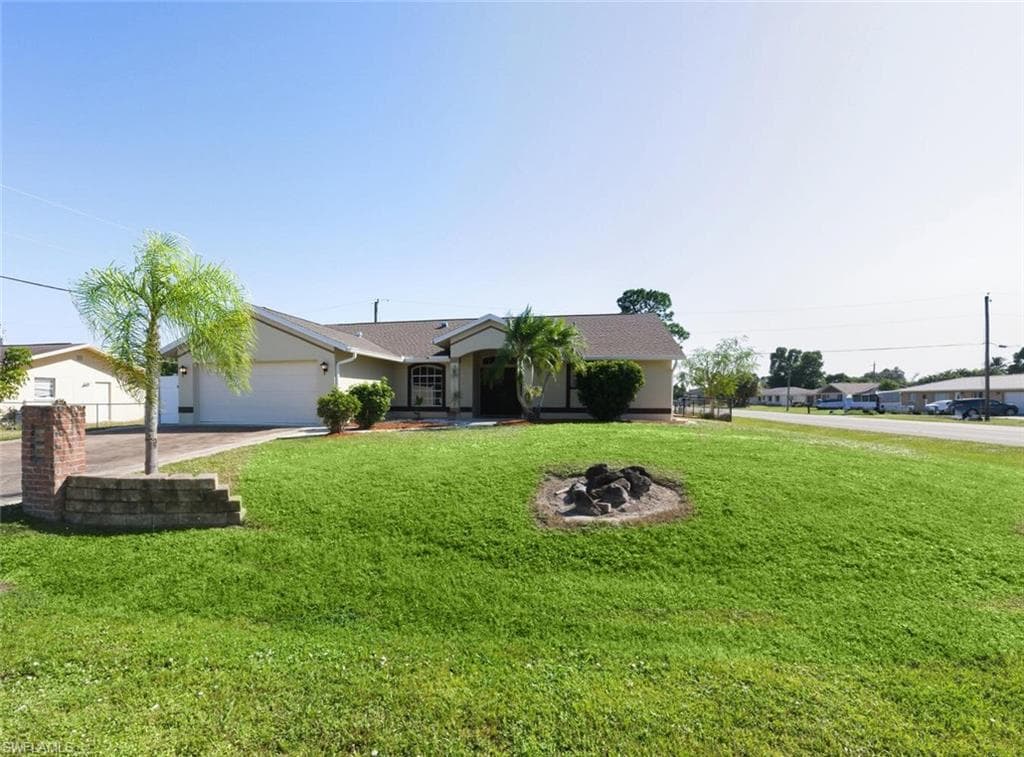 Ranch-style house featuring a front lawn, concrete driveway, stucco siding, and a garage