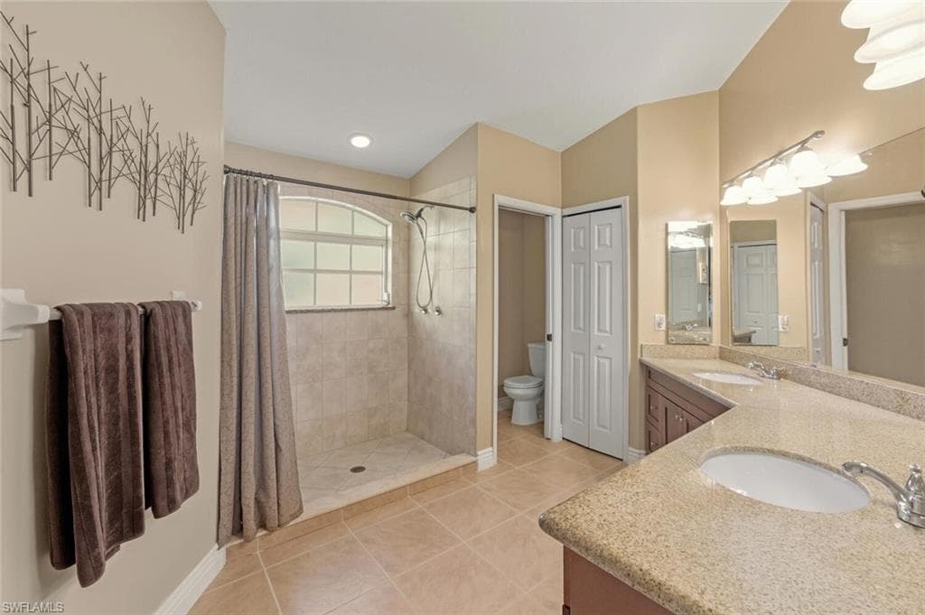 Full bath featuring light tile patterned floors, double vanity, and a shower stall