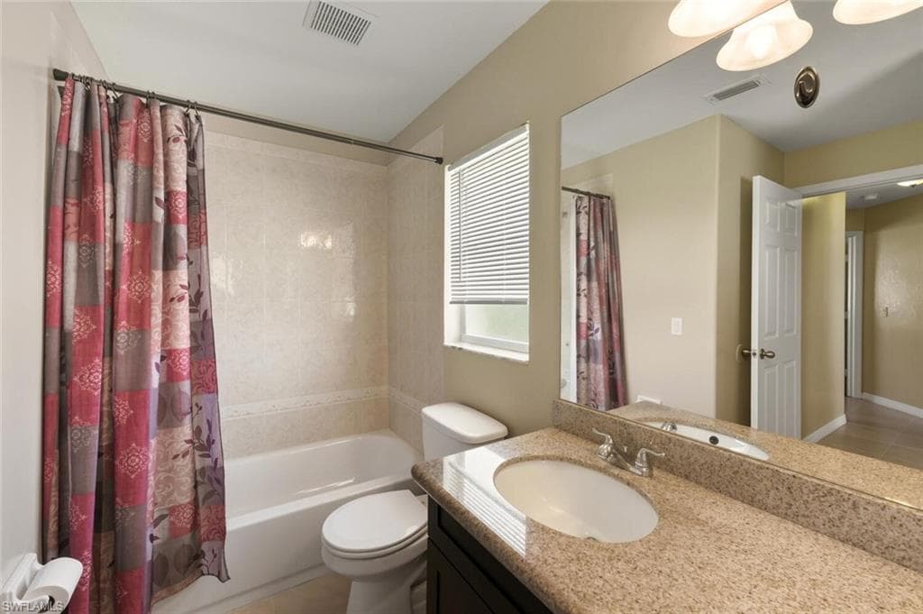 Bathroom with shower / tub combo, vanity, and light tile patterned floors