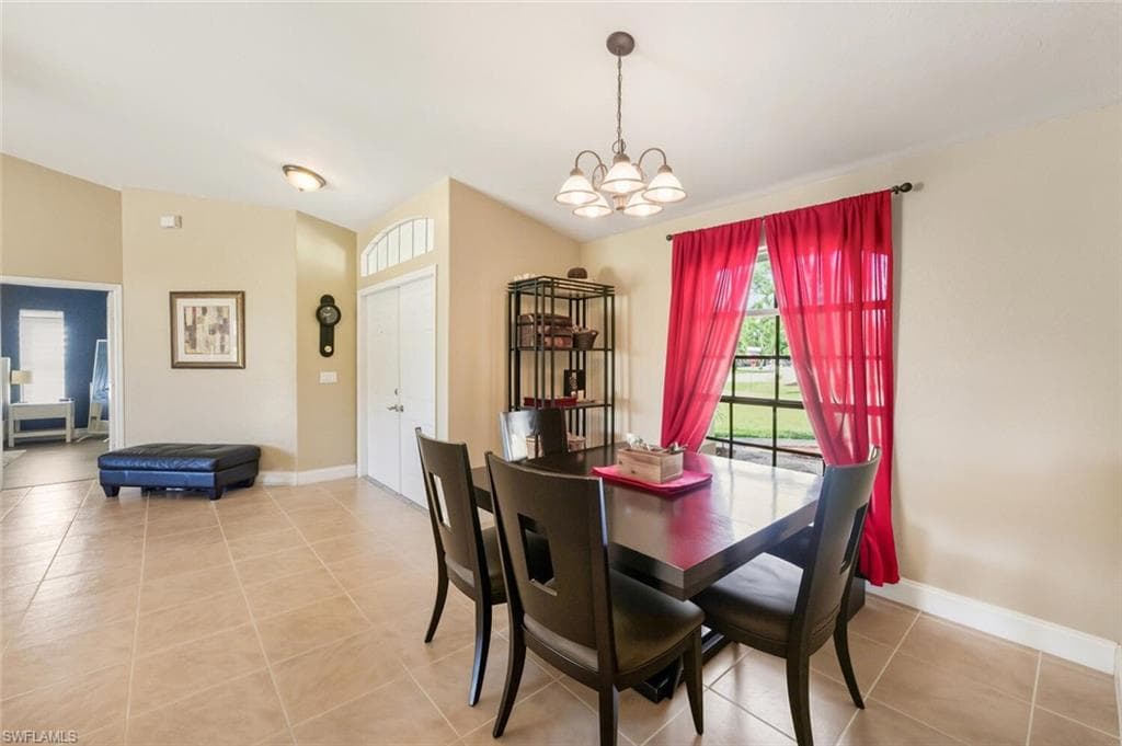 Dining area with light tile patterned floors and a chandelier