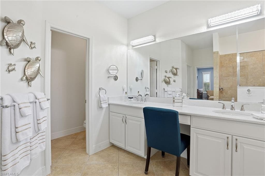 Full bathroom with double vanity, light tile patterned floors, and a tile shower