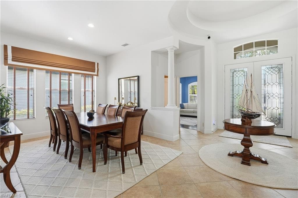 Dining area with healthy amount of natural light, light tile patterned floors, ornate columns, and recessed lighting