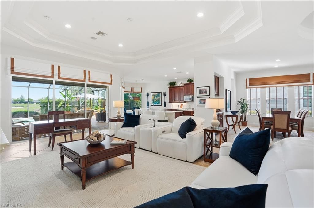 Living room featuring a tray ceiling, recessed lighting, and ornamental molding