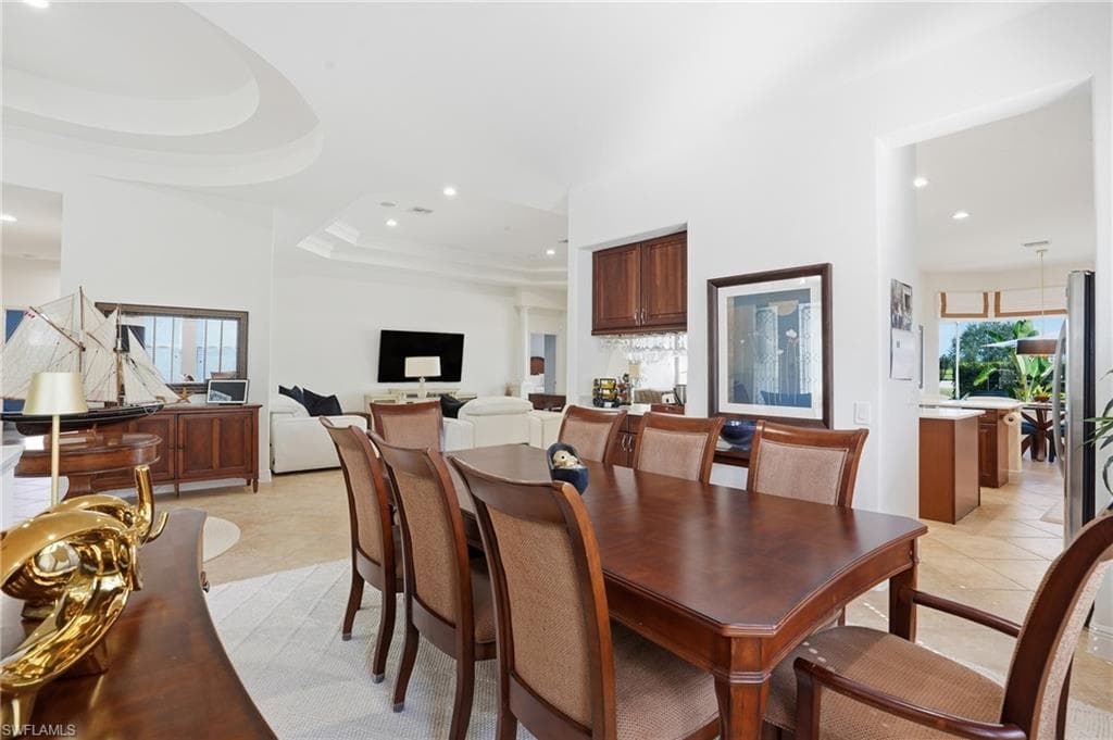 Dining space with a raised ceiling, healthy amount of natural light, recessed lighting, and light tile patterned flooring