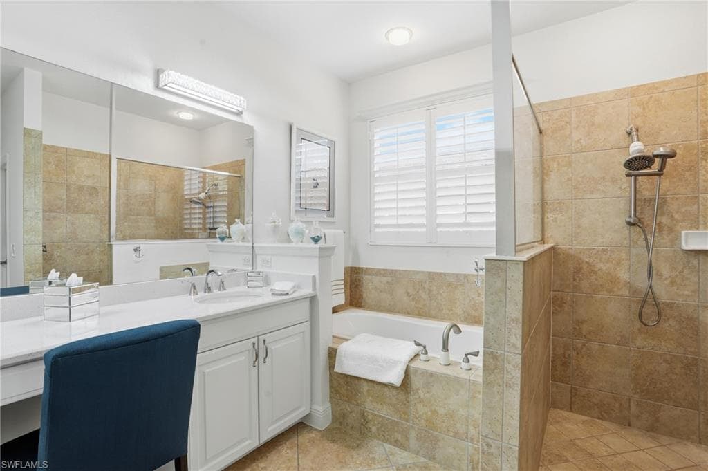 Bathroom featuring a garden tub, vanity, a walk in shower, and light tile patterned floors