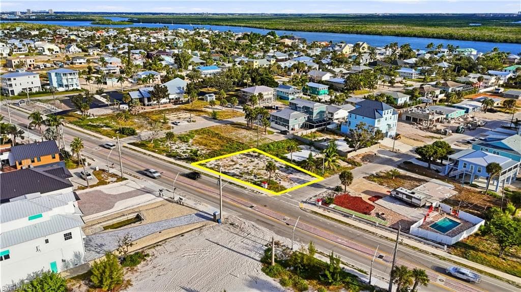 Aerial perspective of suburban area with property parcel outlined and a nearby body of water - Virtually Edited Image