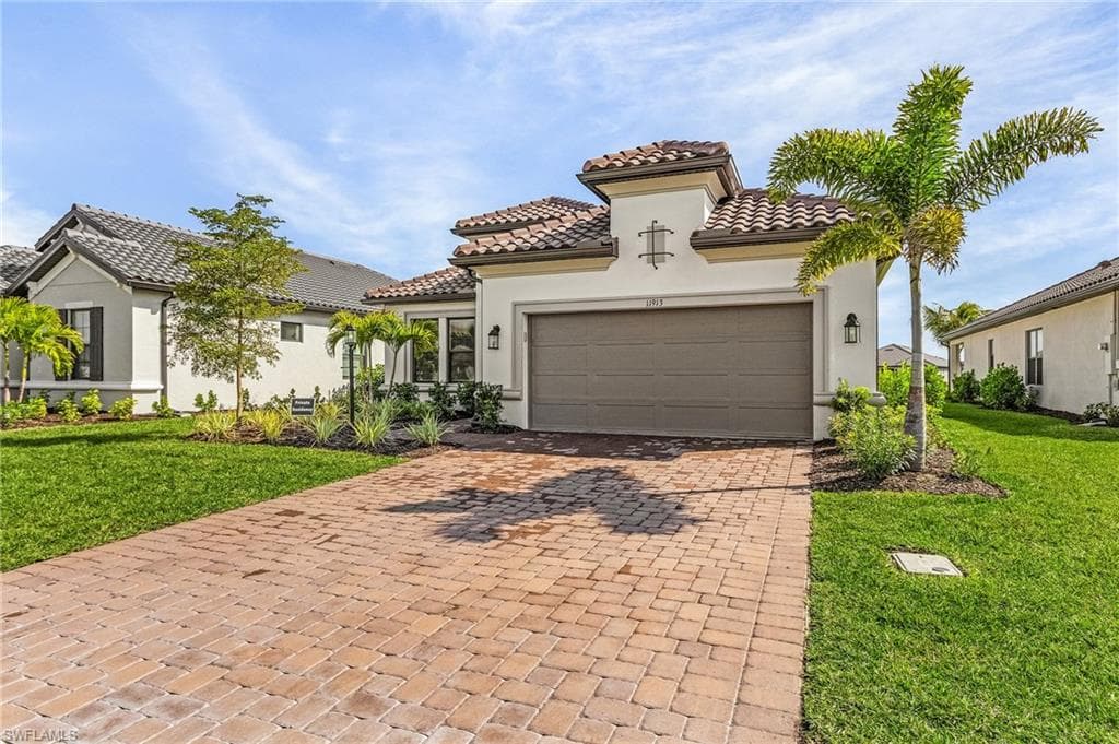 Mediterranean / spanish-style home with a garage and a front lawn