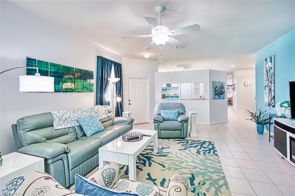 Living area featuring tile patterned floors and a ceiling fan