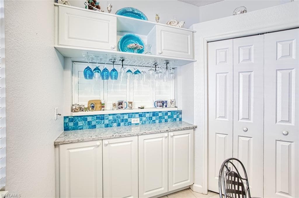 Mudroom with light tile patterned floors and bar