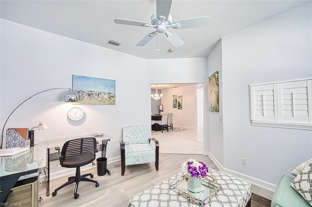 Office area with wood finished floors, ceiling fan, and a chandelier