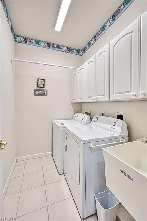 Laundry area with light tile patterned floors, cabinet space, and washing machine and clothes dryer