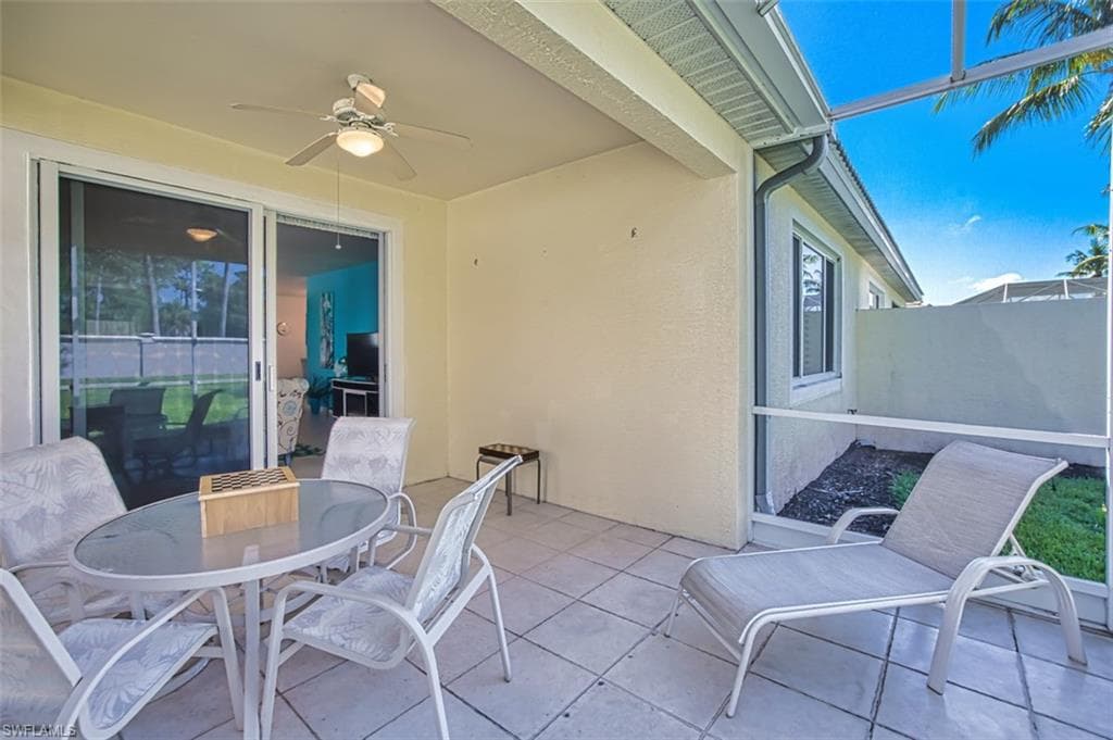 View of patio featuring ceiling fan, outdoor dining space, and a lanai