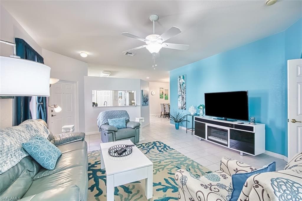 Living area featuring light tile patterned floors and ceiling fan