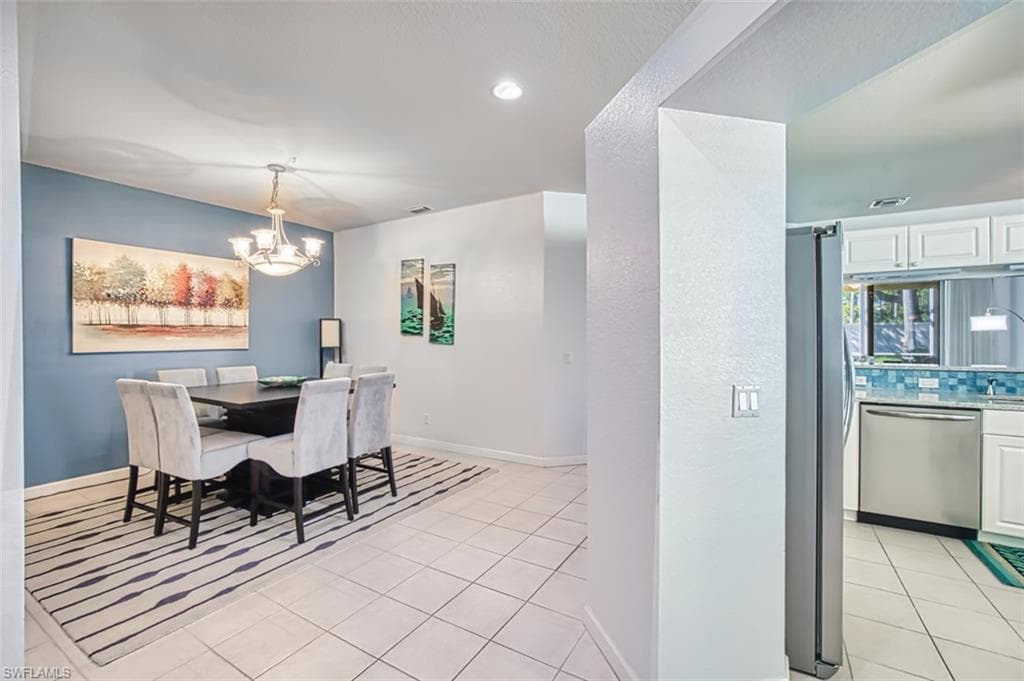 Dining space with light tile patterned flooring, a chandelier, and recessed lighting