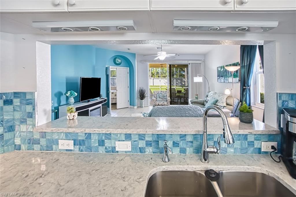 Kitchen featuring ceiling fan, light stone countertops, and open floor plan