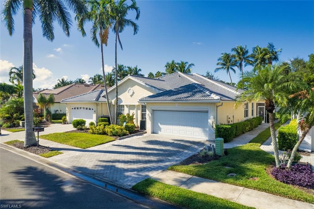 Single story home featuring decorative driveway, a tile roof, stucco siding, a garage, and a front yard