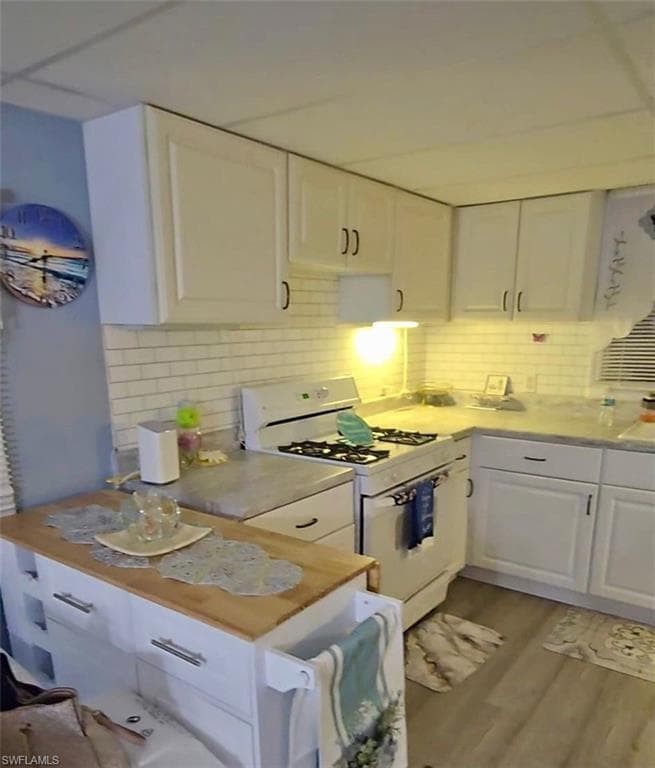 Kitchen with white cabinets, white range with gas cooktop, backsplash, light wood-style flooring, and light countertops