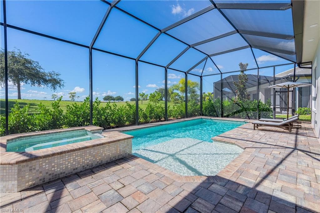 View of swimming pool with a sunroom, a patio area, glass enclosure, and a pool with connected hot tub