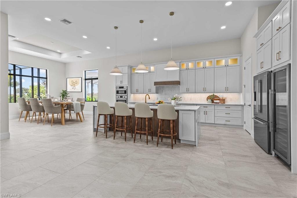 Kitchen with decorative backsplash, a breakfast bar area, pendant lighting, glass insert cabinets, and recessed lighting